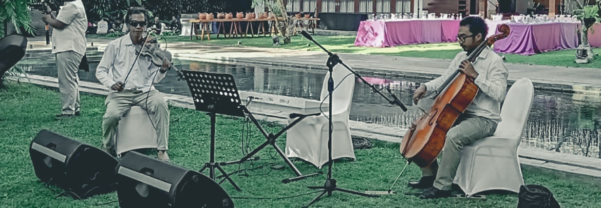 A group of musicians at Villa Tirtadari playing music in front of a pool at a wedding ceremony