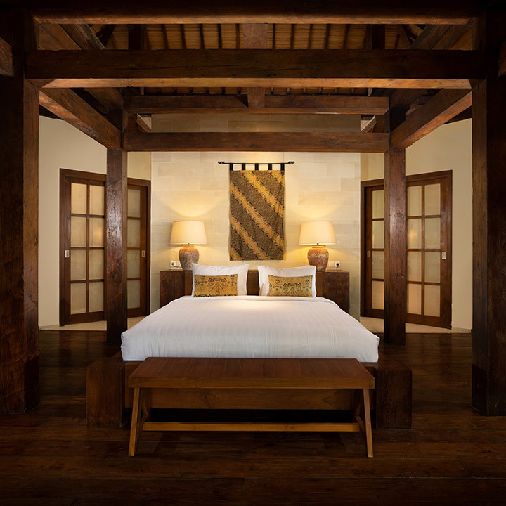 Villa Tirtadari - a luxurious joglo-themed bedroom with a bed and a wooden bed divan in kerobokan.